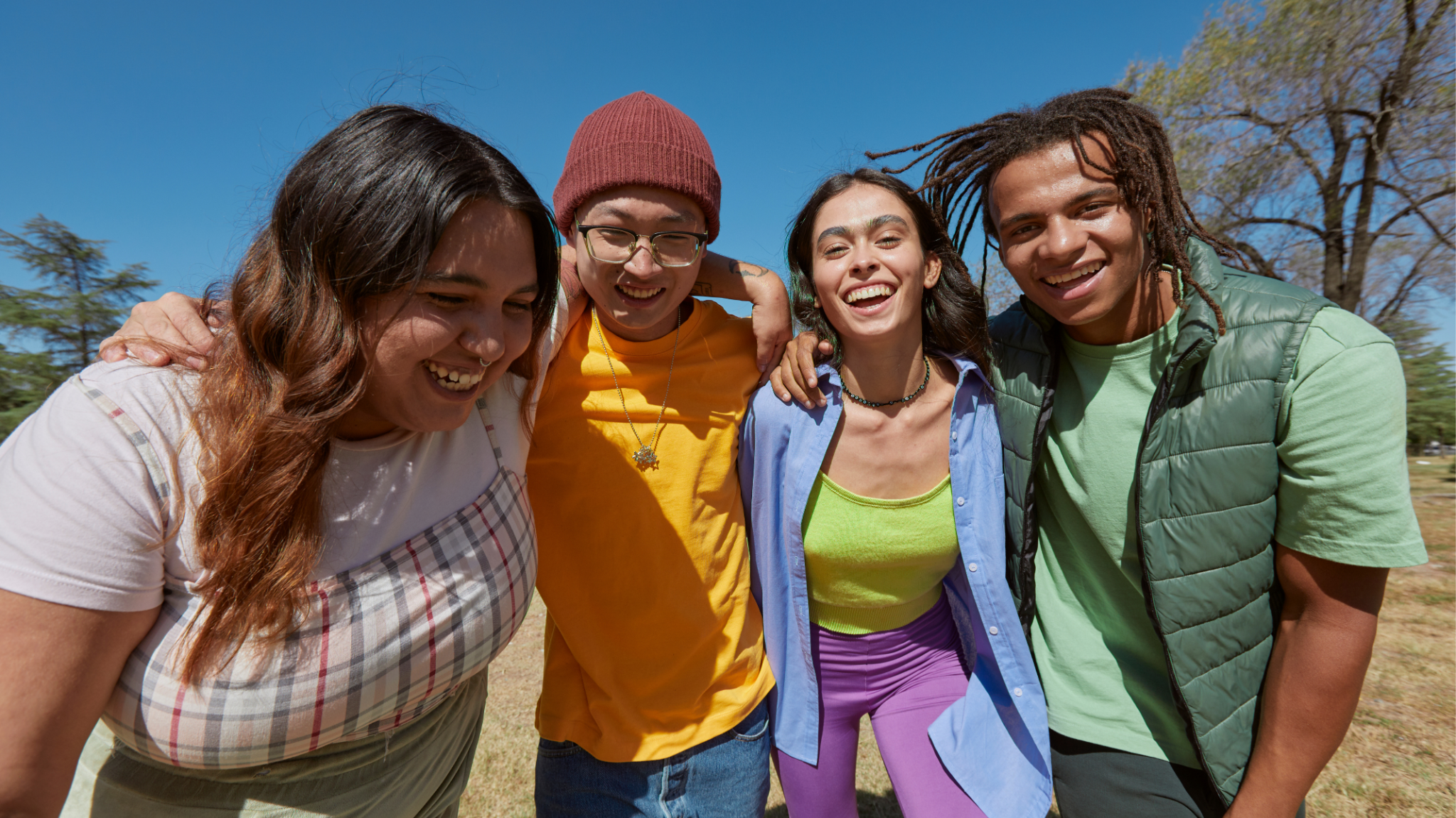 A diverse group of young people laughing together outdoors